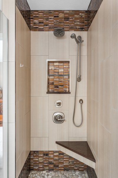 This enlarged shower includes a seat for comfort and two sources of water for an enhanced shower experience. The mixture of tile creates an elegant feel to the space. Two recessed niches provide ample storage for soaps, shampoos, and other bathing essentials. Note the wall tile is the same used on the bathroom floor. Photo 3 of Bathroom Remodel for 1980s Indianapolis Home modern home