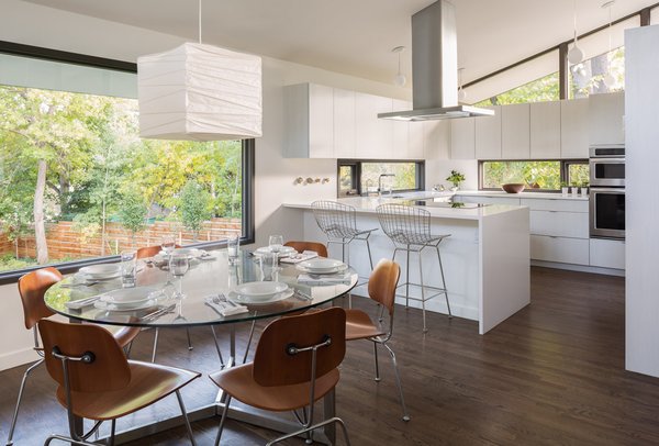 Without increasing the size of the kitchen, we reworked the space to create a family friendly design. This was accomplished by moving the range to the island, adding counter seating and increasing storage with full height cabinetry. New larger windows were added in the dining room to replace small punch openings and natural lighting in the kitchen was improved by adding low counter height windows. Photo 4 of Mid Century Re-Modern modern home