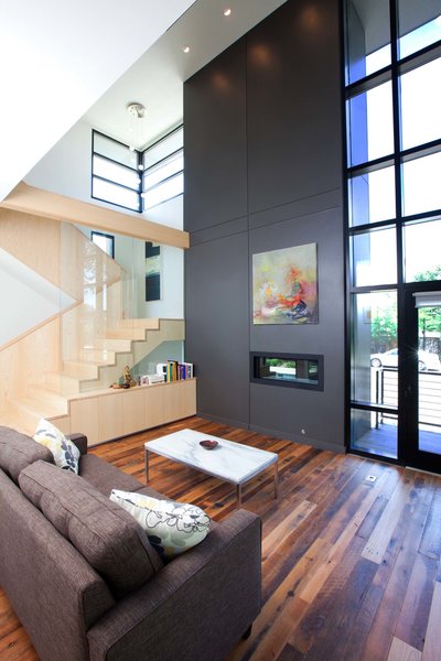 Key to the interior design is the incorporation of natural ash wood elements. These are used on the loft railing, featured cabinetry and showcased on the vertical staircase. The ash kitchen/ dining ceiling bulkhead completes the idea of linear circulation. The terminus on axis with the ash linear bulkhead is the living room fireplace, incorporated in the chimney form which reinforces its street presence. Photo 5 of City Cottage modern home