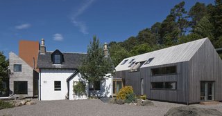 Merging Old and New With These 10 Modern Renovations in Scotland - Photo 2 of 10 - The Old Farmhouse at Invergarry was built in 1868 and has been in the Grant family for more than a century. So, it was fitting that the current owners enlisted their architect daughter, Mhairi Grant, to renovate the home to suit their modern needs. Mhairi designed a double-height internal space while retaining the historical façade, and replaced the outbuildings with two contemporary guesthouses—which connects to the main home through a glass corridor. The renovation, completed in 2014, also features a Cor-Ten tower to house the library with a third floor viewing platform. 