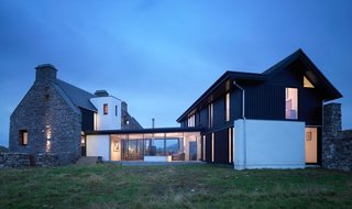 10 Dwell-Approved, New-Old Homes in the UK - Photo 3 of 18 - The White House was originally built in the mid-1700s on the Isle of Coll, but was subsequently abandoned for over 150 years. With only ruins remaining, the owners enlisted WT Architecture to complete a renovation that would incorporate what was left of the former structure with a modern and low-impact home. The result is a stunning mix of the original stone façade with new large windows that frame the ocean view.