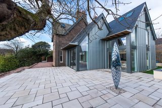 Merging Old and New With These 10 Modern Renovations in Scotland - Photo 5 of 10 - In 2016, Hyve Architects completed the renovation of The Gables, a heritage home in Stonehaven. A modern extension features an open kitchen and family room that connects to the main stone home. The double-pitched roofline of the new structure references the end gable line of the original house.