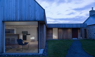 Merging Old and New With These 10 Modern Renovations in Scotland - Photo 8 of 10 - This previously abandoned granite, 18th-century farmhouse in the Scottish Highlands was restored and extended by Moxon. The addition—that's clad with larch and red metal—references the gabled roofline of the original structure and is connected via a glass passageway.