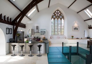7 Repurposed Churches Around the World - Photo 8 of 8 - In Kelso, Scotland, a centuries-old stone church was converted into a five-bedroom house—which you can actually rent out—where the upper floor of the church is one large, open space that houses a kitchen, dining area, living room, and game space. The open plan also allows attention to be focused on the pointed arch windows along the front facade.