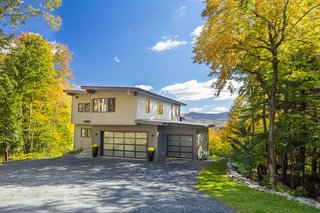 12 Modern Marvels in New England - Photo 3 of 12 - The Mad River Modern by Yankee Barn Homes is a 21st Century take on the Mid-Century Modern style. The home was built on a sloped site, but would work equally well on a level lot. An open floor plan and floor-to-ceiling windows allow for maximum natural light and integration with the outdoors. A neutral color palette emphasizes the natural warmth of the post and beam frame. The open living plan progresses seamlessly to the outdoors through over-size windows and doors. Built in the Green Mountains of Vermont by avid outdoor enthusiasts, the Mad River Modern allows complete engagement with the out-of-doors, even on a cold day when tucked snugly inside by a cozy fire!