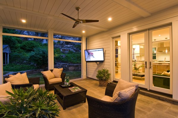 The covered porch makes for a stunning outdoor living space that is very suited for life in New England. This porch is generous in scale and extends off the open concept living areas of the Kitchen and Family room of the home. An outdoor entertainment system with surround sound and a television, built for outdoor use from SunBrite TV, makes this a great gathering space. Photo 2 of Greenwich Modern Barn modern home