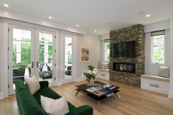 Opposite of the kitchen in the open concept heart of the home is the family room complete with surround sound and television for an evening of movies. Expansive windows and double french doors lead to the covered porch. The fireplace features stacked stone used around the property forming a design connection between the outside landscape and interior of the home. Photo 7 of Greenwich Modern Barn modern home