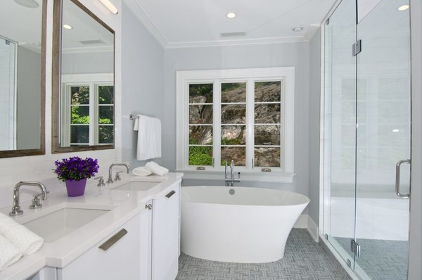 The master suite includes a gorgeous bath with heated floors, a luxurious soaking tub, and oversized shower with built in waterproof speakers. The cabinets that make up the vanity were extended slightly for the sinks allowing for visual interest and extra counter space behind the faucets.
The mirror lined medicine cabinets provide amble space and are accented with strips of reclaimed barn wood carrying through the modern barn theme of the home. Photo 10 of Greenwich Modern Barn modern home