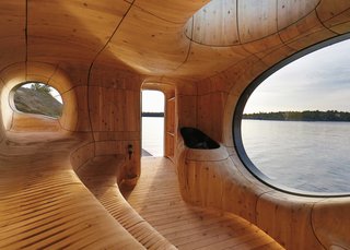 Escape to One of These 10 Otherworldly Outdoor Saunas - Photo 7 of 10 - The space is lined with CNC-cut wooden panelling that creates a sinuous interior encompassing traditional stepped sauna seating and biomorphic-shaped porthole windows.