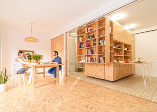 Located outside of the bathroom in the corner of the apartment, the storage units contain a fold-out bed, work surfaces, and shelves when fully closed. 