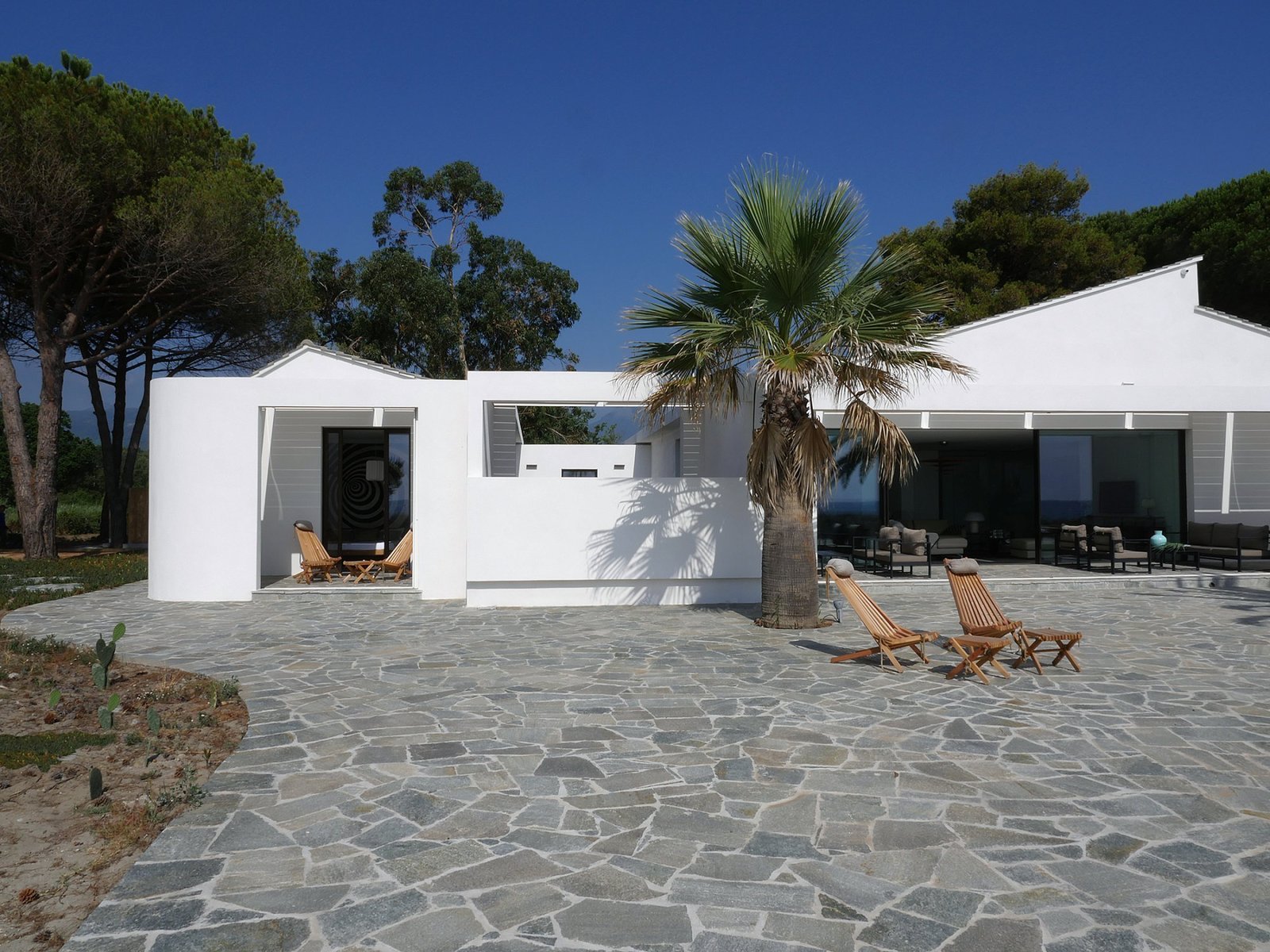 Located steps from the beaches of Corsica, this striking modern beach house was designed by Paris-based architect Vincent Leprince, as a bright and bold reference to the sunshine-washed coastal surroundings. It features living room doors that open onto a terrace with panoramic views, and that leads directly to the beach. The home is tastefully decorated with contemporary furnishings and includes a heated spa with views of the island of Monte Cristo.