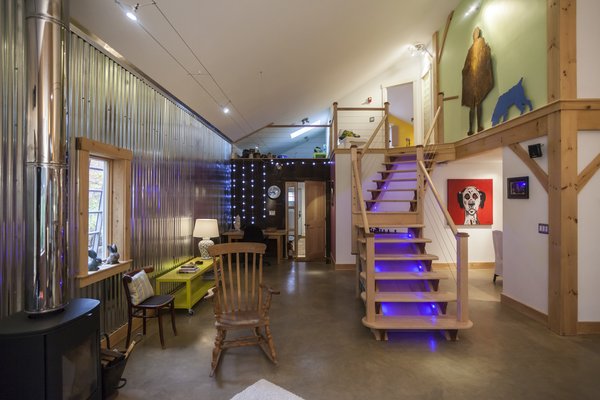 The main room cathedral space is anchored by a hand built maple and walnut staircase, with its own integrated lighting system. The stunning corrugated expanse along the whole length of the main room gives a dramatic contrast to the new barn board north elevation and the old barn born used in small discreet areas. Photo of The Bath House modern home