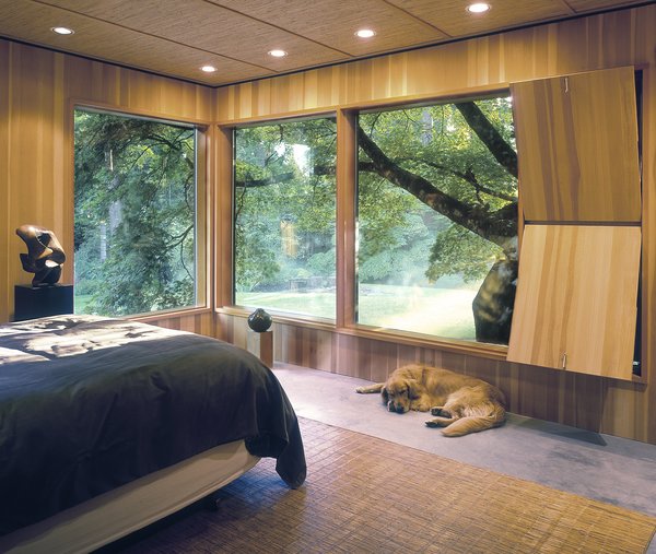 The Master Bedroom features wide expanses of windows overlooking the 2-acre garden. The adjacent original wood "ventilator" hides a series of wood louvers that can be exposed or closed depending on the air flow need. The concrete floor features radiant heat, further visual warmth is supplied by the room's wood paneled walls and ceiling. Photo 6 of Belluschi Addition modern home