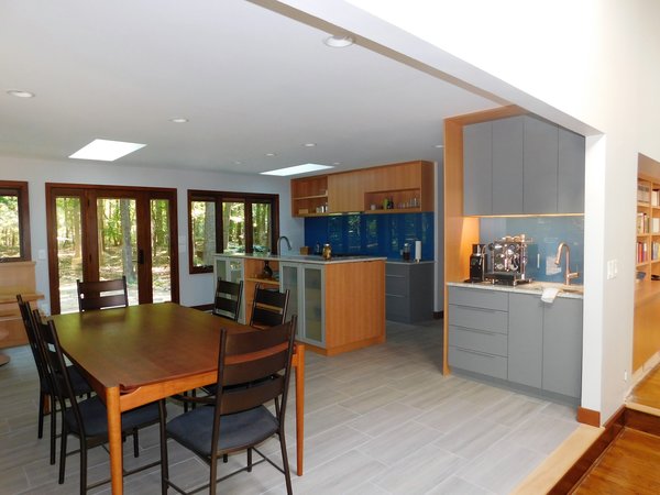 Modern home with wood cabinet, ceramic tile floor, colorful cabinet, stone counter, glass tile backsplashe, recessed lighting, range, range hood, refrigerator, dishwasher, beverage center, drop in sink, and dining room. Custom fir cabinets from Wayne Foushee of Cabinet Creations; Glass backsplash from Brad Loder of Environite; stone counters and tile floor from Custom Stone and Marble of Durham; Windows and doors from Ehrich Thomas of Coastal Window and Door; Plumbing by Sparrow & Sons; Electric by Theye Electric; Appliances provided by The Appliance Center of Durham. Photo of The Mason Project