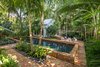 Modern home with Outdoor, Back Yard, Trees, Shrubs, Garden, Gardens, Walkways, Hardscapes, Large Pool, Plunge Pool, Lap Pool, Swimming Pool, Standard Construction Pool, Pavers Patio, Porch, Deck, Landscape Lighting, and Large Patio, Porch, Deck. The coping of the pool was raised, as the owners wanted the property to feel as though it was spilt in half, allowing the guesthouse to feel separate and private from the main house. Tall palms were used for their canopies and plantings were done by groupings of the same varieties to help the garden feel open and spacious. Photo 10 of Key West Classic