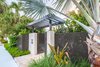 Modern home with outdoor, trees, grass, shrubs, front yard, hardscapes, pavers patio, porch, deck, large patio, porch, deck, metal fence, walkways, horizontal fence, landscape lighting, and garden. The Bismarckia Palm was not only used as a focal point but it also blocks the view of the neighbors into the cantilevered office. The step up into the property was done as the grade had to be made up between the street and the house therefore it was done gradually by adding the first step up into the property. Photo 2 of Key West Modern