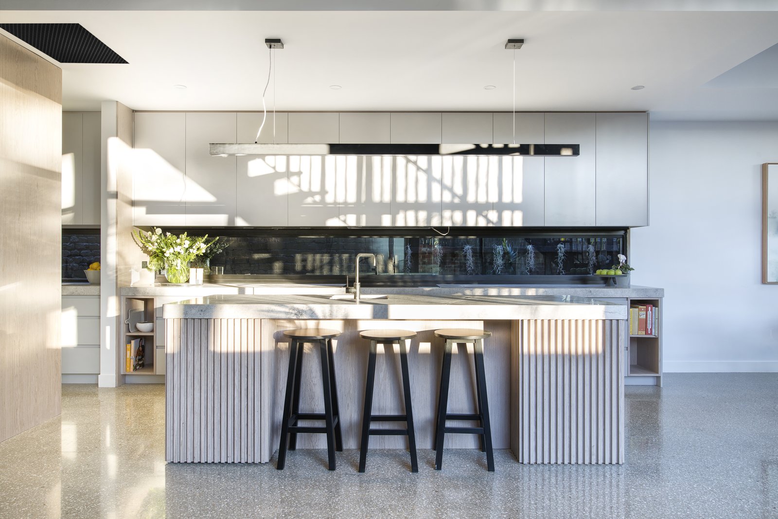The interior palette in the extension includes bespoke limed oak cabinetry from the kitchen to the bathroom, fabricated by local outfit Panorama Cabinets, polished concrete floors, and black steel accents, such as in the open-tread staircase and windows.