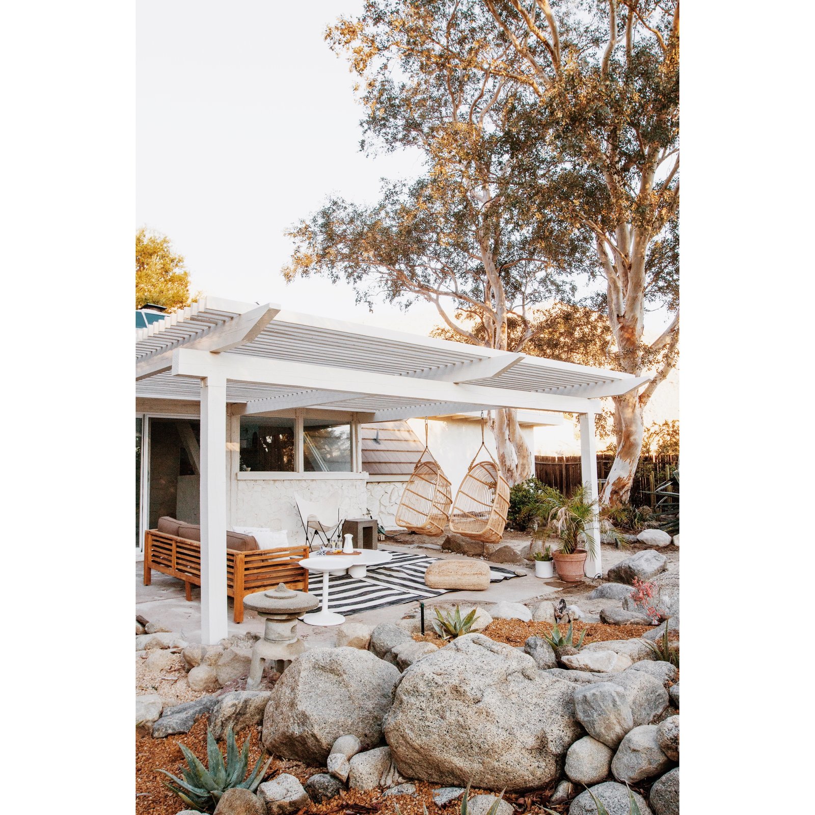 This pergola-covered seating area, complete with hanging chairs, is off the living room.