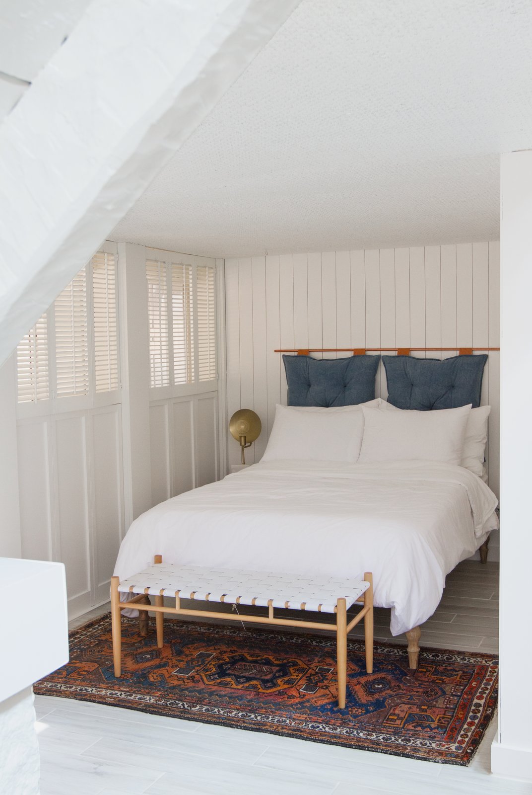 Off the living room, Samuel uses this den as a second sleeping spot, or "guestroom nook." Crumbling basket-weave texture was covered with painted wood paneling and the headboard is a DIY.