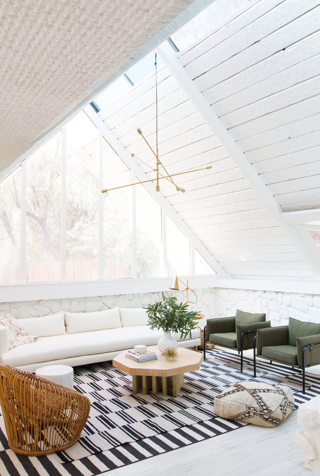 In the living room, Samuel painted the exposed wood and stonework to unify the space and let the original texture step forward. (The wood had been painted already by previous owners.) A custom ten-foot sofa sits below the window and the green canvas armchairs are from Urban Outfitters.