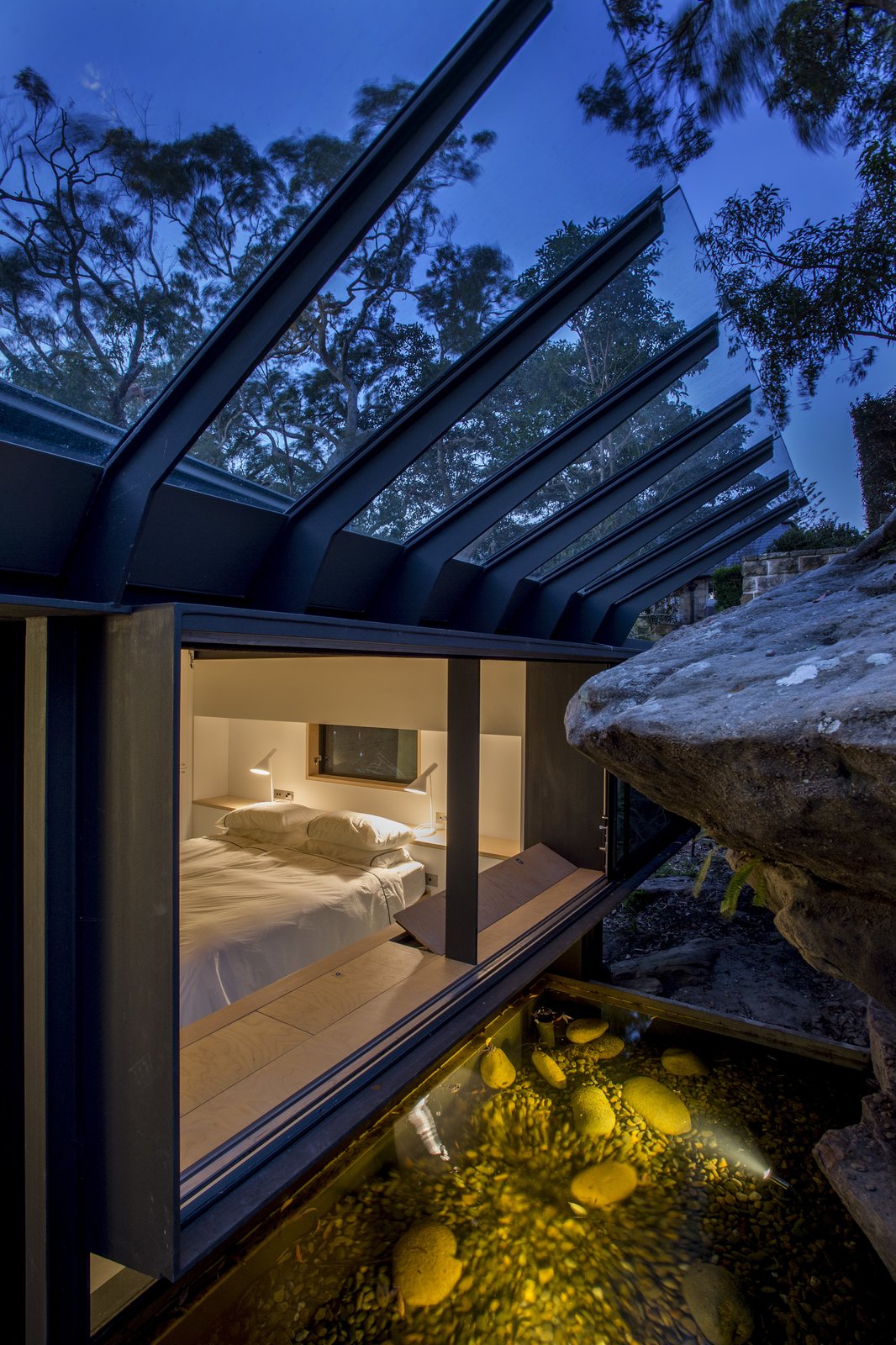 The principle bedroom windows embrace the sandstone rock face. A sloped glass roof shields rain.