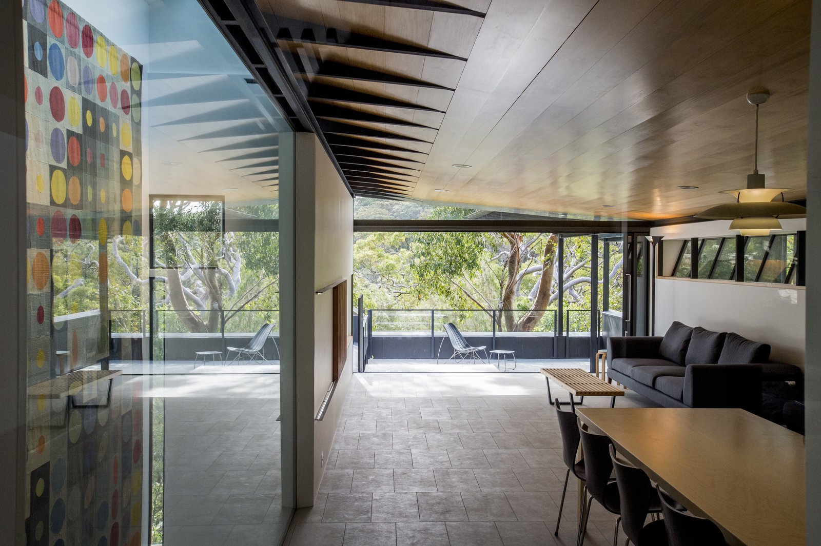 The open plan living area, complete with sealed concrete floors and ceilings lined with hoop pine, looks out on a 366-square-foot veranda and has views towards the natural estuary of Pittwater.