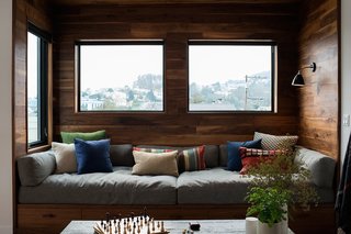 10 Cozy Spaces and 15 Products to Help You Get Ready For Fall - Photo 5 of 10 - A walnut-wrapped nook in the living room of an apartment renovation in San Francisco by SF Design Build includes a built-in window seat that's complete with plush cushions and pillows. Multiple windows and a wall-mounted light ensure that the space receives plenty of light.
