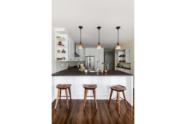 Modern home with kitchen, metal counter, white cabinet, recessed lighting, pendant lighting, medium hardwood floor, ceramic tile backsplashe, refrigerator, range, range hood, and drop in sink. A view of the kitchen from the dining room. This kitchen is both traditional and modern in style to match the existing home with a fresh updated look. New white cabinets and floors patched and refinished to match the existing are paired with Rejuvenation Tractor Stools and Copper pendants, Neolith Iron Copper countertops, and Heath Ceramics tile backsplash. Photo 2 of 14th Avenue Remodel