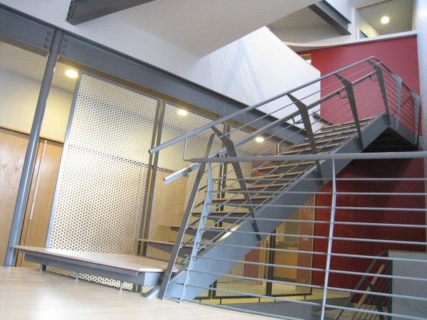 looking NE from the dining room into the solar chimney: steel tube single stringer. ¼” folded steel cantilevered brackets form the treads/risers. ¾” oak applied wearing surface. ¼” steel verticals, ½” rod balusters w/1 ½” steel top tube rail. steel angle frame w/perforated aluminum infill screen, entry hall beyond. transom at upper tight is in the hall bath shower. Photo 13 of metalHOUSE(2) modern home