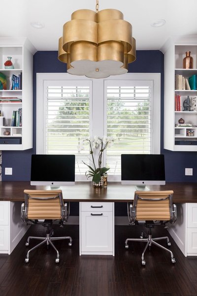 Across from the craft area we built a custom 30" deep desk with stained pecan top, central trash bin pull out, file storage on either side, and concealed wire storage cabinet with an easy access panel. An accent wall of Serena & Lily wallpaper and chandelier by Aerin really bring an elegant touch to this home office. Photo 3 of Mueller Home Office modern home