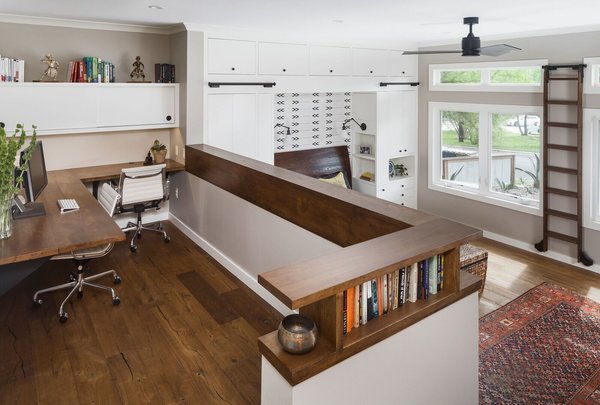 We created a platform at the entry of the bedroom so you could walk into the room at the same level as the rest of the house. Creating this platform allowed easy access to the new home office location and master bathroom. Prior to the remodel you had to walk down the stairs into the bedroom and up more stairs to get into the bathroom. This area is accented by a gorgeous floating pecan desk, open shelving that acts as a decorative railing, and an original brick wall that we discovered during construction. Photo 2 of Barton Hills Bedroom modern home
