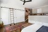Walking down the stairs will lead you to the master bedroom which features floor to ceiling custom cabinets at the bed wall, deep drawers below the platform wall, and custom closet with sliding doors. Access to all of the cabinets was a must, even at the tippy top, so we designed a library ladder that could be used on the closet or bed side, with a central resting place between the windows when not in use. The overall aesthetic is warm, clean and minimal, with white cabinets, stained European white oak floors, and matte black hardware. An accent wall of Cavern Home wallpaper adds interest and ties the finishes of the room together. Photo 8 of Barton Hills Bedroom modern home
