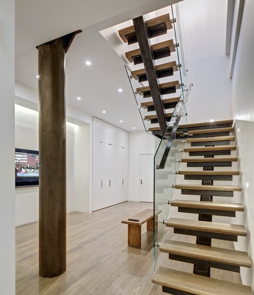 Modern home with interior, metal, sliding door type, metal tread, wood tread, metal railing, glass railing, and staircase. Staircase: View of Lower Level Family Room
The biggest single challenge was in the design and fabrication of the staircase. The stair was required to be both code and child safety compliant. The staircase’s unique features include the co-planar clear-tempered glass-rails and the child-proof open slots under the welded bent steel angles. Supported by a sizable post concealed in the wall behind the stair, stair attachments are made with moment connections. All metalwork on this job, including the stairs and door panels were site fabricated forging a unique hand-crafted industrial product, difficult to shop replicate. Photo 10 of Noho Duplex, New York