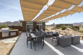 Owner Dave McAdam started Blue Sky Building Systems, whose steel-frame system easily adapts to sloped lots, before founding Homestead Modern, whose pre-designed homes can be built nearly anywhere for a set price. Above, a shaded patio off the main house enjoys access to a fire pit and a grill.