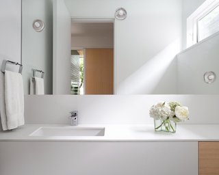The bathroom palette blends seamlessly into the whole floor plan with white oak accents and decorative lighting. 