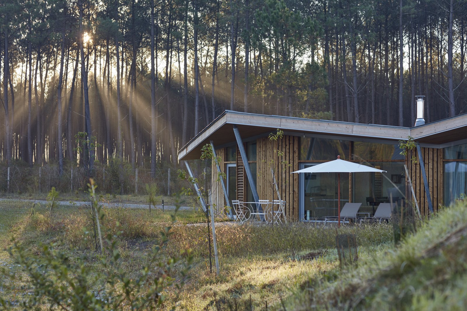 Maritime pines from the Landes Forest compose the exterior wood cladding of each hut and purposefully form the incredible views outward to the lake. The wood frame segues into an angular, butterfly roof that collects and directs rainwater back into the lake. Furthermore, it provides shading where full-height windows open into the living space. By orienting each hut in the same direction, the architects create a sense of isolation within the wood enclosure.