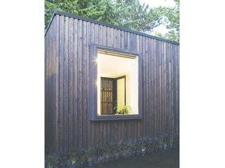 A Modern Micro-House in Portland Clad in Local Fir - Photo 7 of 8 - The custom screen door is visible on the far side of the space. Windows are strategically located to frame views of the exterior landscape. 