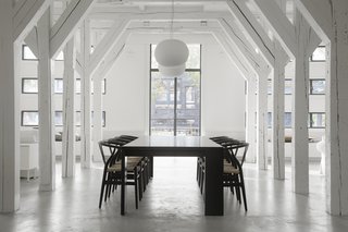 A Converted Warehouse in Amsterdam Boasts Soothing Interiors of Concrete and Wood - Photo 2 of 9 - Hans J. Wegner Wishbone Chairs surround the large dining table on axis with the grand, exterior windows. 