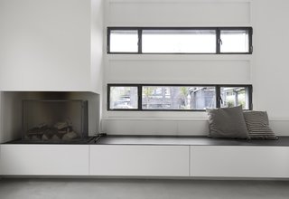 A Converted Warehouse in Amsterdam Boasts Soothing Interiors of Concrete and Wood - Photo 4 of 9 - Custom benches with integrated storage and a fireplace sit below the windows lining the exterior walls of the open living space.