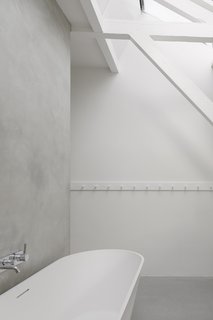 A Converted Warehouse in Amsterdam Boasts Soothing Interiors of Concrete and Wood - Photo 9 of 9 - A white, freestanding solid surface tub by Riho Barcelona and a Zuchetti faucet outfit an additional bath, blending nicely into the minimal palette.