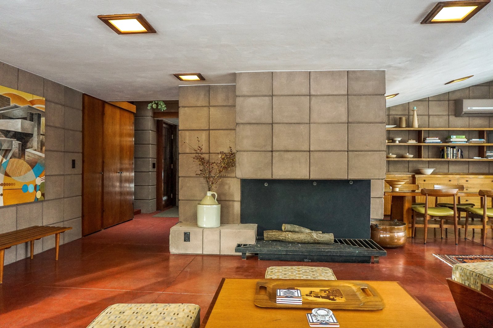 Living and dining spaces wrap around the full-height fireplace. Original light fixtures remain and have been outfitted with LED lights.