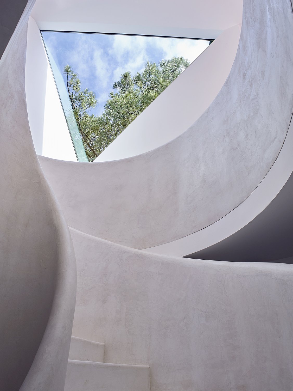 The curvilinear staircase, painted all white, contrasts with the angular forms evident throughout the home.