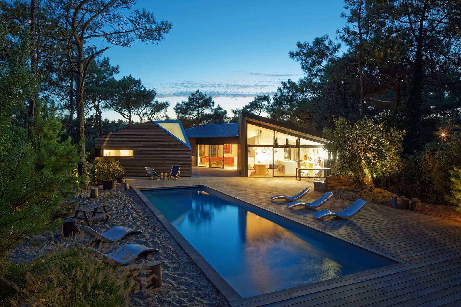 At sunset, the holiday home glows like a shining lantern set within the forest.