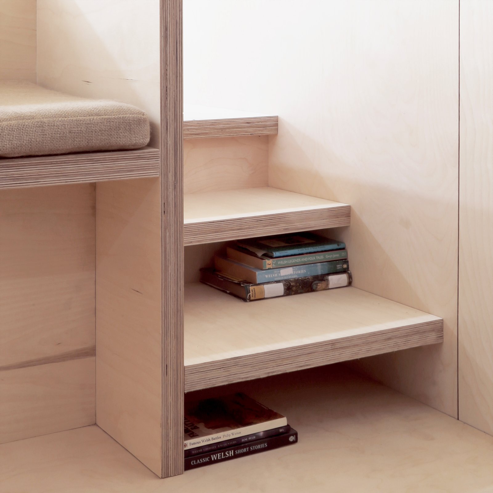 Stairs leading up to the platform bed double as storage for books.