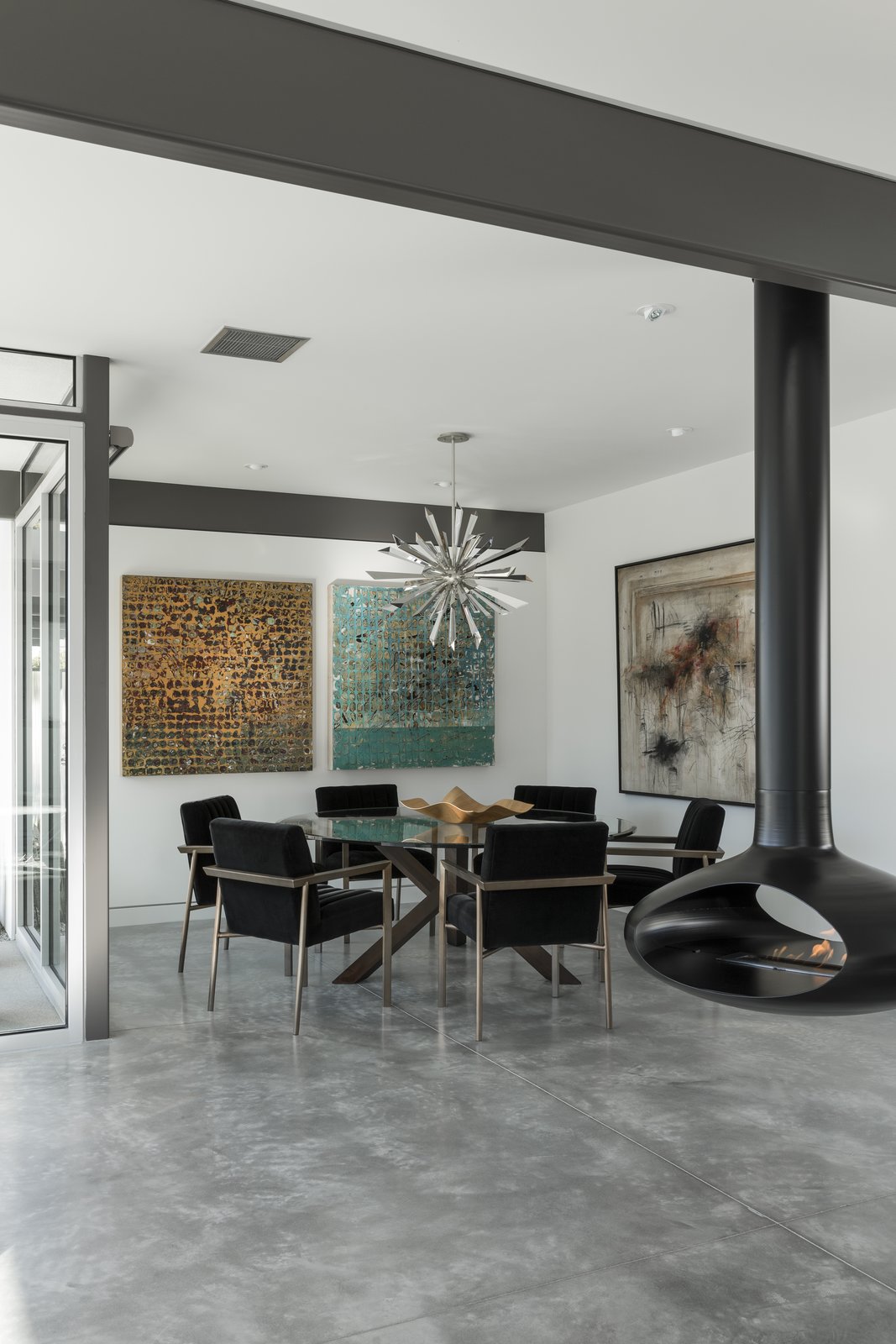 Modern furnishings, a decorative metallic pendant, and colorful artwork decorate the dining space.
