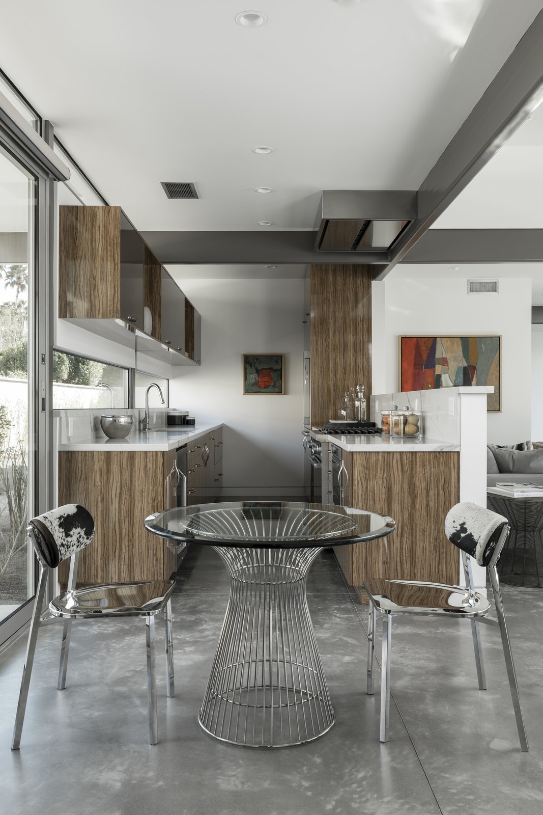 A contemporary kitchen with wood cabinetry provides an open, fluid cooking space. The cooktop hood nestles perfectly against the structural framing.