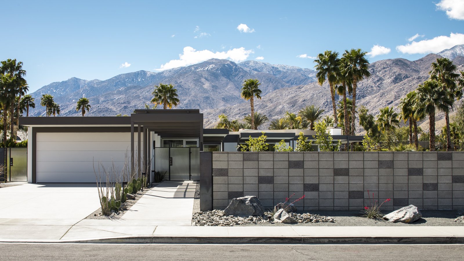 A steel framed canopy leads directly to the front entry of the dwelling. A concrete block fence provides privacy from the surrounding neighborhood. Drought tolerant landscaping dots the landscape.