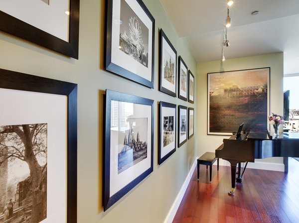 Modern home with hallway and medium hardwood floor. John is an avid world traveler and photographer. He took these photos (left) on one of his journeys to Thailand. We had them framed and hung in this bold arrangement. The Galen Garwood painting at the end of the hall was from their previous home. Originally, its frame was painted a light mauve, reminiscent of the 80s, so we chose to re-paint the frame an espresso/black. The small change brought the whole piece up-to-date. Photo 14 of Downsize Upstyle