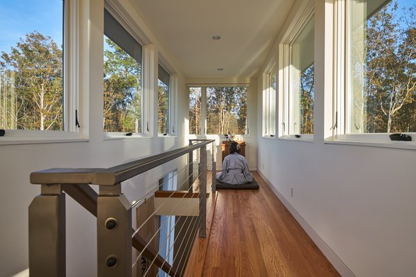 Modern home with living room and medium hardwood floor. The architects designed the home to act as a solar chimney: ventilation flows from the lowest windows on the ground level to the highest windows in the observatory. A modern interpretation of the traditional “widow’s walk”, a third floor yoga room has windows on all sides and serves as a solar chimney, exhausting out hot air. Photo 7 of Mill Pond House