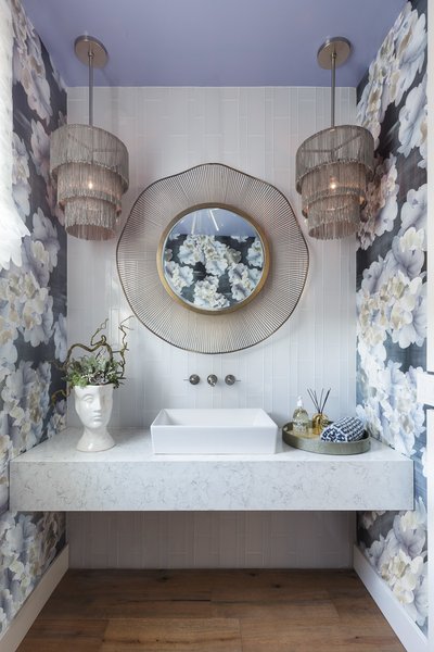 Modern home with bath room, engineered quartz counter, medium hardwood floor, vessel sink, pendant lighting, and glass tile wall. The vanity wall is tiled from floor to ceiling in a white glass tile from Crossville to add a modern contrast yet still remain subtle. The quartz was selected for it’s simplicity and timeless feel. The mirror has an organic feel with the metal rippling around the glass moving in and out in a wave pattern. I like the edgy metal fringe chandeliers for a hint of movement. Photo 2 of Traditional Home Napa Valley Showhouse